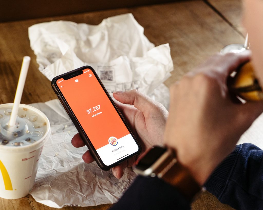 Person eating a burger and using their phone